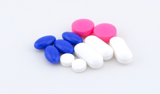 Assorted coated and uncoated pharmaceutical tablets in white, blue, and pink colors inspected using BiSmart 2.0 for quality and defect detection.